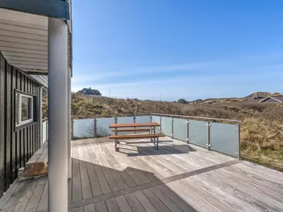 a wooden deck with a bench on the side of a house at Holiday Home Swerting - 230m from the sea by Interhome in Saltum
