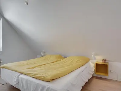 a bedroom with a bed with a yellow blanket on it at Holiday Home Riki - 150m from the sea by Interhome in Blokhus
