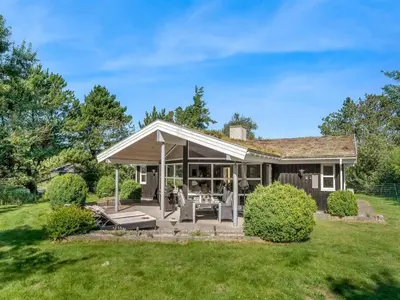 a house with a porch with a lawn at Holiday Home Bina - 1-9km from the sea by Interhome in Blokhus