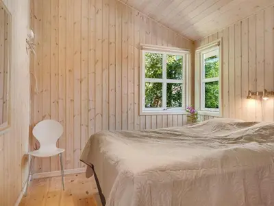 a bedroom with a bed and a chair in it at Holiday Home Bina - 1-9km from the sea by Interhome in Blokhus
