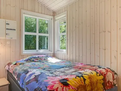 a bed in a room with two windows at Holiday Home Bina - 1-9km from the sea by Interhome in Blokhus