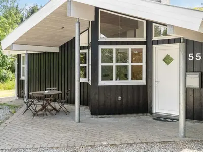 a black house with a white door and a table at Holiday Home Bina - 1-9km from the sea by Interhome in Blokhus
