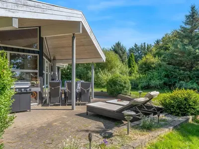 a patio with a table and a grill in a yard at Holiday Home Bina - 1-9km from the sea by Interhome in Blokhus