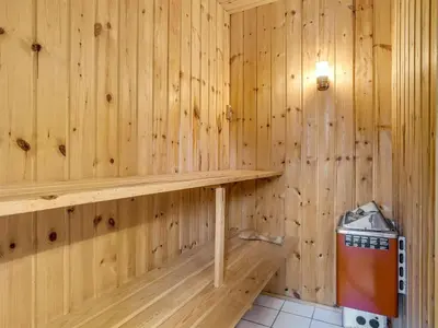 a wooden sauna with a bench and a trash can at Holiday Home Hereth - 700m from the sea by Interhome in Saltum