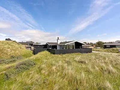 a house on the top of a grassy hill at Holiday Home Kiina - 100m from the sea by Interhome in Blokhus