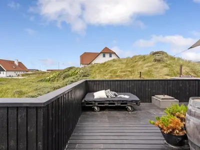 a bed on a wooden deck with a hill at Holiday Home Kiina - 100m from the sea by Interhome in Blokhus