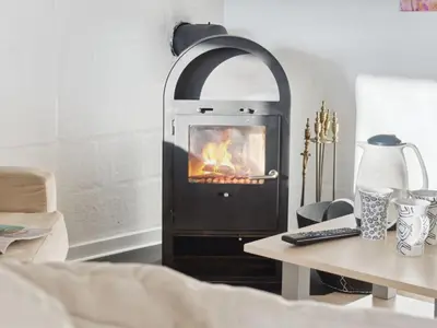 a fireplace in a living room with a table and a table at Holiday Home Gerwin - 3km from the sea by Interhome in Blokhus