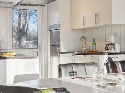 a kitchen with white cabinets and a table and chairs at Holiday Home Gerwin - 3km from the sea by Interhome in Blokhus
