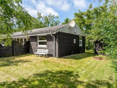 a small house with a bench in the yard at Holiday Home Gerwin - 3km from the sea by Interhome in Blokhus