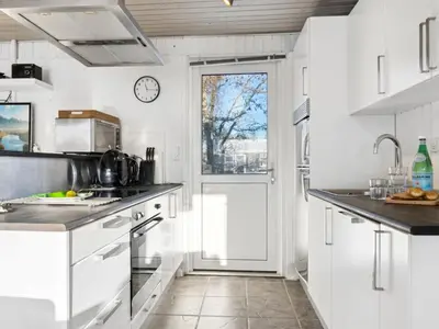 a kitchen with white cabinets and a clock on the wall at Holiday Home Gerwin - 3km from the sea by Interhome in Blokhus