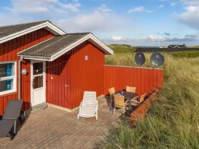 a red building with a table and chairs in front of it at Holiday Home Dana - 290m from the sea by Interhome in Saltum