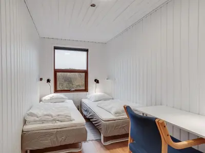 two beds in a room with a window and a chair at Holiday Home Jobst - 150m from the sea by Interhome in Saltum