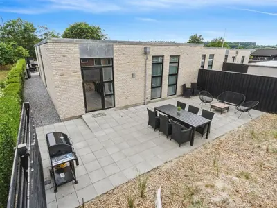 a patio with a grill and a table and chairs at Holiday Home Laulu - 2km from the sea by Interhome in Blokhus
