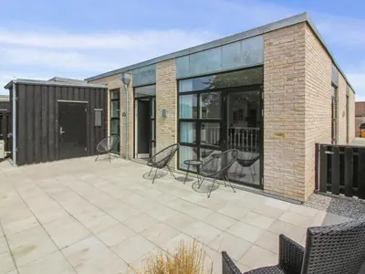 a patio with two chairs and a building at Holiday Home Laulu - 2km from the sea by Interhome in Blokhus