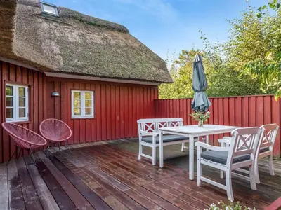 a patio with a table and chairs and an umbrella at Holiday Home Beghel - 350m from the sea by Interhome in Blokhus