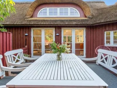 a white table with a vase of flowers on a patio at Holiday Home Beghel - 350m from the sea by Interhome in Blokhus