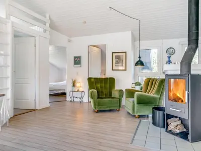 a living room with two green chairs and a fireplace at Holiday Home Nilson - 1-4km from the sea by Interhome in Blokhus