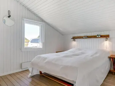 a white bedroom with a bed and a window at Holiday Home Nilson - 1-4km from the sea by Interhome in Blokhus