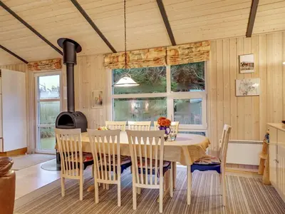 a dining room with a table and chairs and a stove at Holiday Home Sighwarth - 350m from the sea by Interhome in Saltum