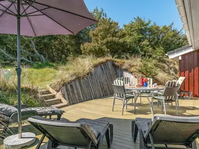 a patio with a table and chairs and an umbrella at Holiday Home Sighwarth - 350m from the sea by Interhome in Saltum