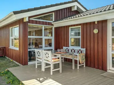 a house with a table and chairs on a deck at Holiday Home Sighwarth - 350m from the sea by Interhome in Saltum