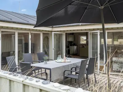 a patio with a table and chairs and an umbrella at Holiday Home Erwith - 50m from the sea by Interhome in Blokhus