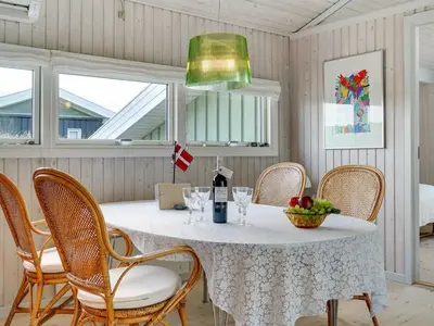 a dining room with a table with chairs and a bottle of wine at Holiday Home Erwith - 50m from the sea by Interhome in Blokhus