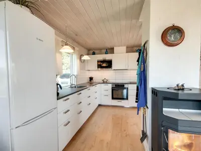 a kitchen with white cabinets and a wooden floor at Holiday Home Diuri - 400m from the sea by Interhome in Saltum