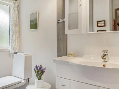 a white bathroom with a sink and a mirror at Holiday Home Eivy - 1km from the sea by Interhome in Saltum