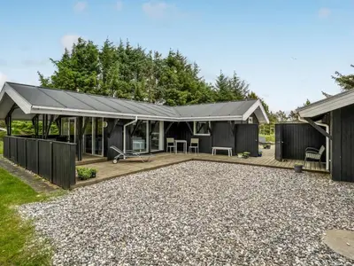 a house with a pitched roof and a patio at Holiday Home Eivy - 1km from the sea by Interhome in Saltum