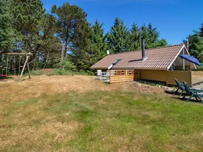 a cabin with a picnic table and a playground at Holiday Home Maritha - 950m from the sea by Interhome in Saltum