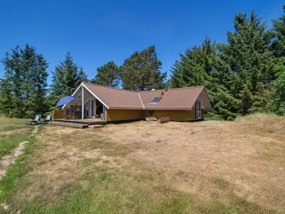 a house on a field with trees in the background at Holiday Home Maritha - 950m from the sea by Interhome in Saltum