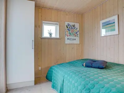 a bedroom with a bed with a blue blanket and two windows at Holiday Home Josten - 500m from the sea by Interhome in Saltum