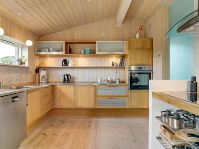 a kitchen with wooden cabinets and wooden flooring at Holiday Home Josten - 500m from the sea by Interhome in Saltum