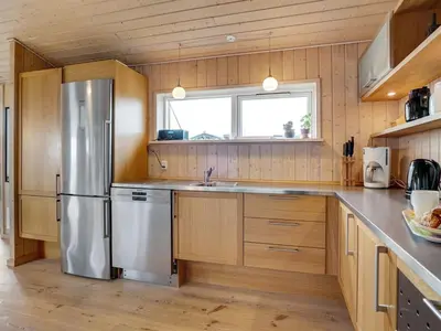 a kitchen with wooden cabinets and a stainless steel refrigerator at Holiday Home Josten - 500m from the sea by Interhome in Saltum