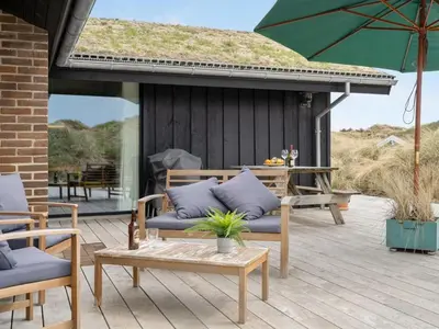 a patio with chairs and a table and an umbrella at Holiday Home Simeona - 140m from the sea by Interhome in Saltum