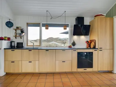 a kitchen with wooden cabinets and a window at Holiday Home Simeona - 140m from the sea by Interhome in Saltum