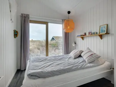 a bedroom with a bed with a large window at Holiday Home Simeona - 140m from the sea by Interhome in Saltum