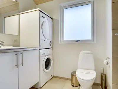 a bathroom with a toilet and a washer and dryer at Holiday Home Ricus - 1-8km from the sea by Interhome in Saltum