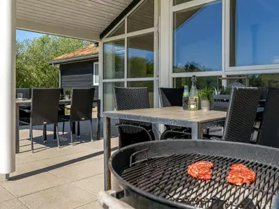 an outdoor patio with a table and chairs and a grill at Holiday Home Ricus - 1-8km from the sea by Interhome in Saltum