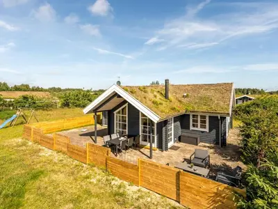 a small black house with a grass roof at Holiday Home Annemie - 1-8km from the sea by Interhome in Saltum