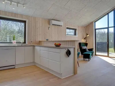 a kitchen with white cabinets and a living room at Holiday Home Bentine - 1-6km from the sea by Interhome in Saltum