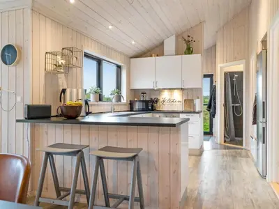 a kitchen with white cabinets and bar stools at Holiday Home Javorka - 1-4km from the sea by Interhome in Saltum