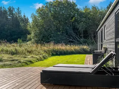 a bed on a deck next to a house at Holiday Home Javorka - 1-4km from the sea by Interhome in Saltum