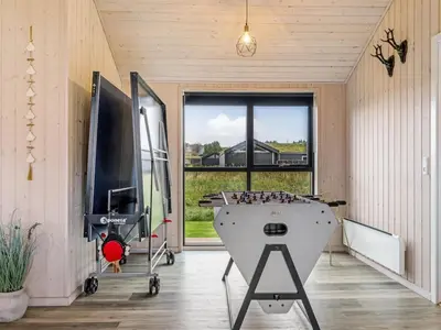 a room with a ping pong table and a large window at Holiday Home Javorka - 1-4km from the sea by Interhome in Saltum