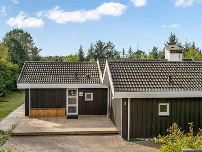a black house with a wooden deck in front of it at Holiday Home Mechthild - 2-7km from the sea by Interhome in Saltum