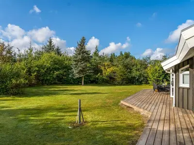 a wooden deck next to a yard with trees at Holiday Home Mechthild - 2-7km from the sea by Interhome in Saltum