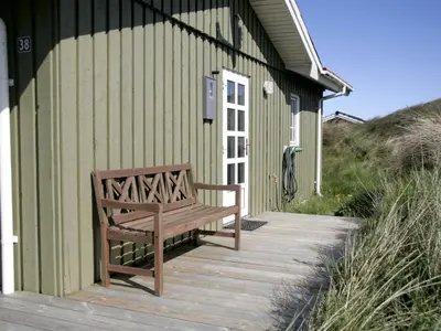 a wooden bench sitting on a porch of a building at Holiday Home Arita - 250m from the sea by Interhome in Saltum