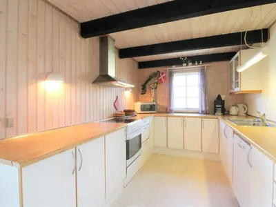 a large kitchen with white cabinets and a window at Holiday Home Arita - 250m from the sea by Interhome in Saltum