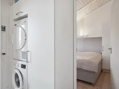 a small bedroom with a bed and a washer and dryer at Holiday Home Dijana - 150m from the sea by Interhome in Saltum